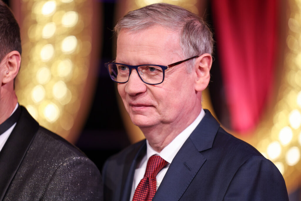 Günther Jauch mit Brille, Anzug und Krawatte befindet sich neben einem anderen Mann