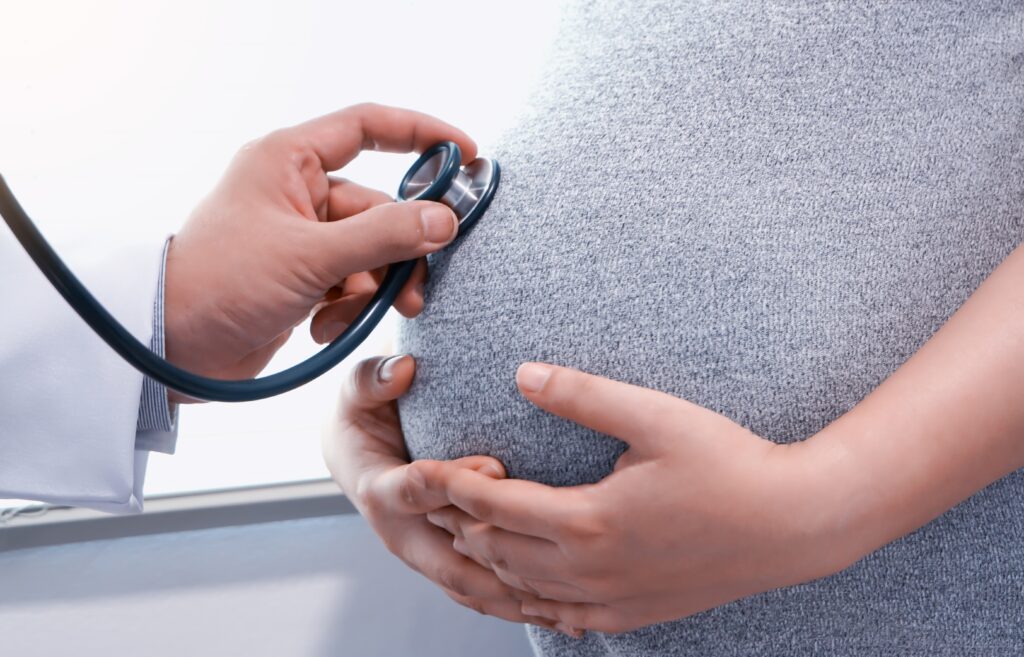 Arzt hört Herztöne von Babybauch ab