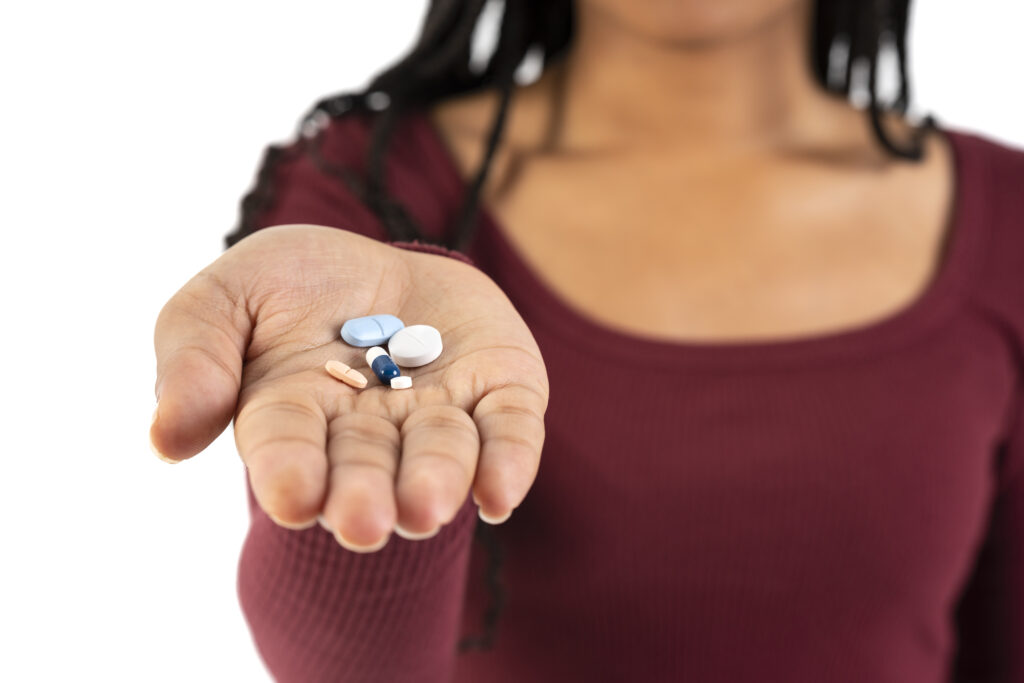 Frau die mit ausgestreckter Hand Tabletten anbietet