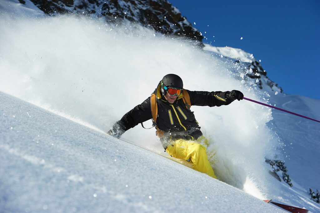 Skifahrer auf steilem Abhang mit gelber Skihose