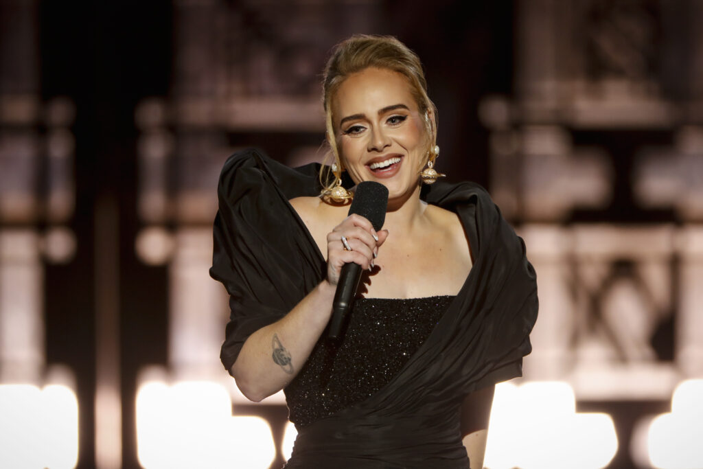 Adele in einem schwarzen Kleid mit einem Mikrofon in der Hand