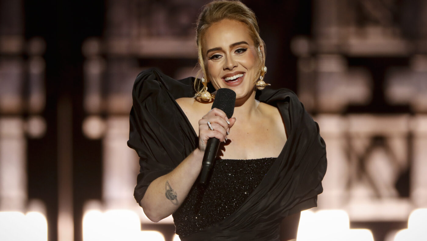 Adele in einem schwarzen Kleid mit einem Mikrofon in der Hand