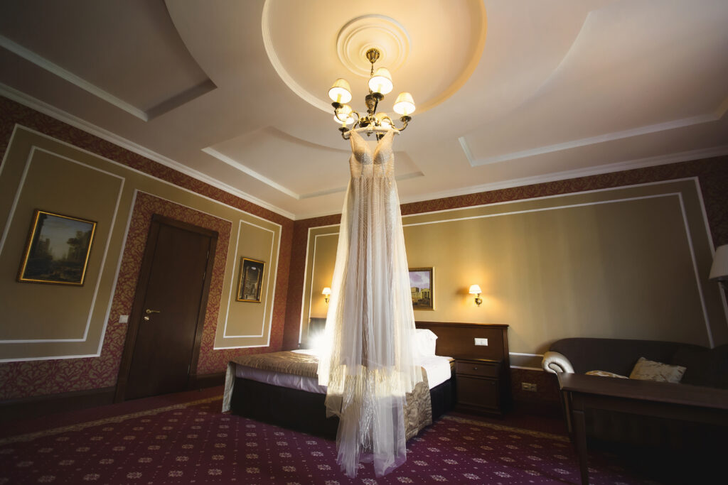 Luxuriöses weißes Hochzeitskleid hängt  in einem Hotelzimmer