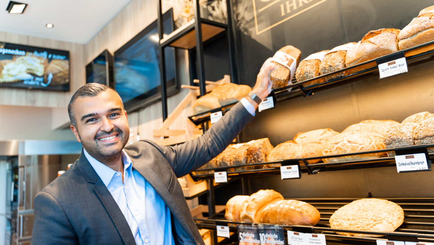 Eyüp Aramaz sthet in einer Bäckerei und hält Brot in der Hand