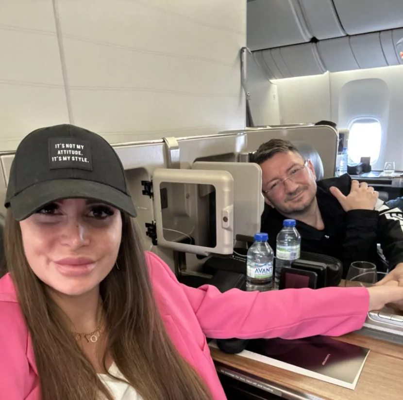 Susi mit rosa Sakko und schwarzer Kappe sitzt neben Walter Temmer im Flugzeug