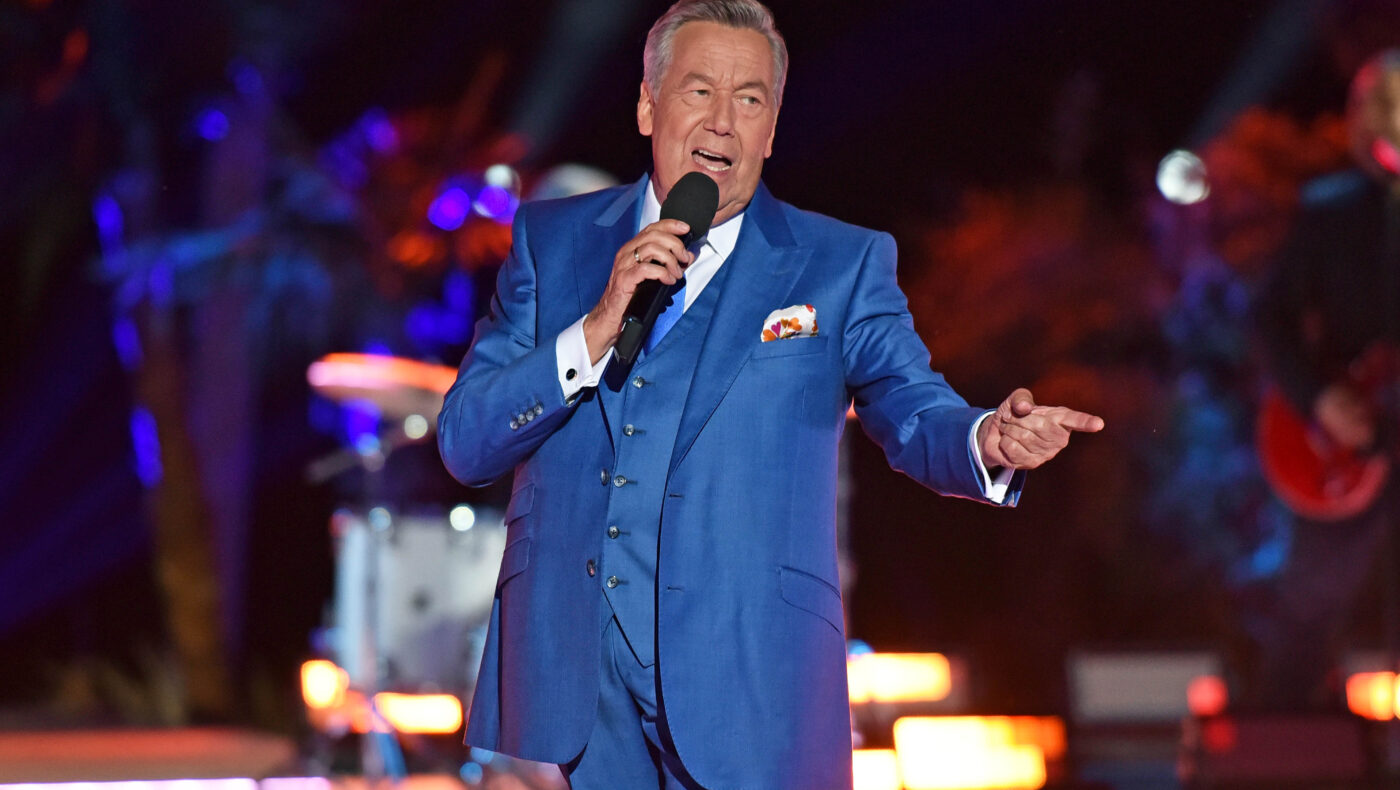 Roland Kaiser steht in blauem Anzug auf der Bühne und hält Mikrofon in der Hand