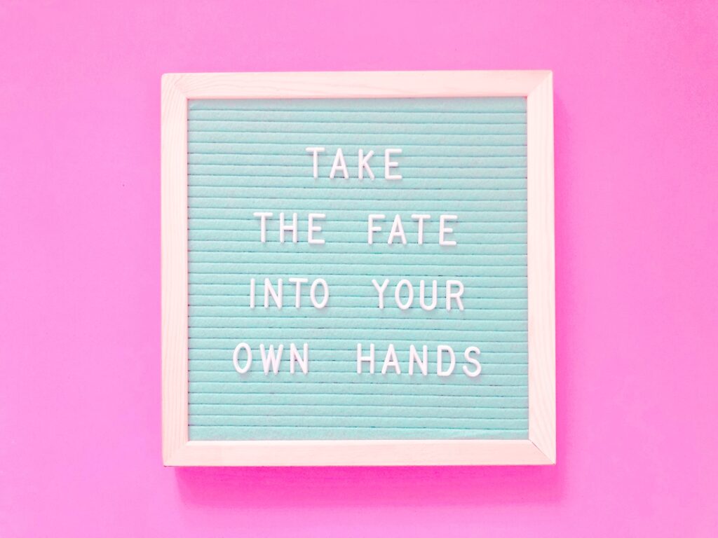 Pinker Hintergrund auf dem in einem hellen Rahmen auf türkis-gerilltem Papier der Spruch: TAKE THE FATE INTO OUT OWN HANDS steht