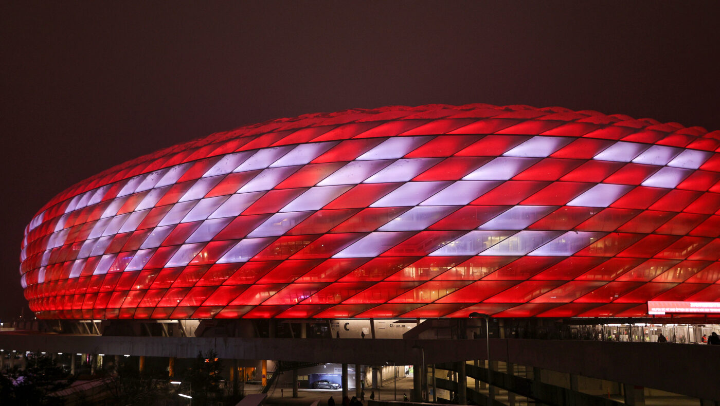 Allianz Arena in München, gehüllt in Bayern-München-Farben und der Laufschrift 