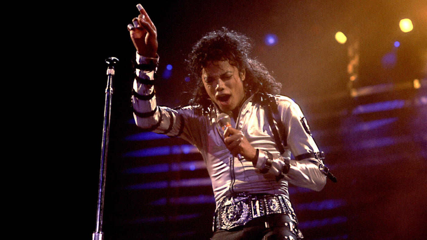 Michael Jackson steht auf der Bühne und hält Mikrofon in der Hand
