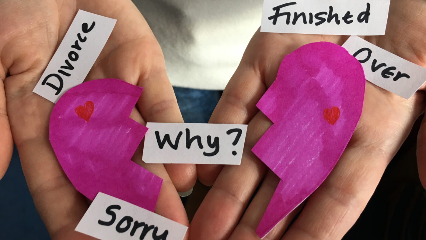 Hände mit geteiltem pinken Herz und de Worten Sorry; Why, finished und Divorce