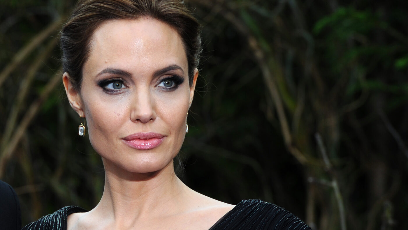 Angelina Jolie mit schwarzem Oberteil und Ohrringe blickt in die Kamera