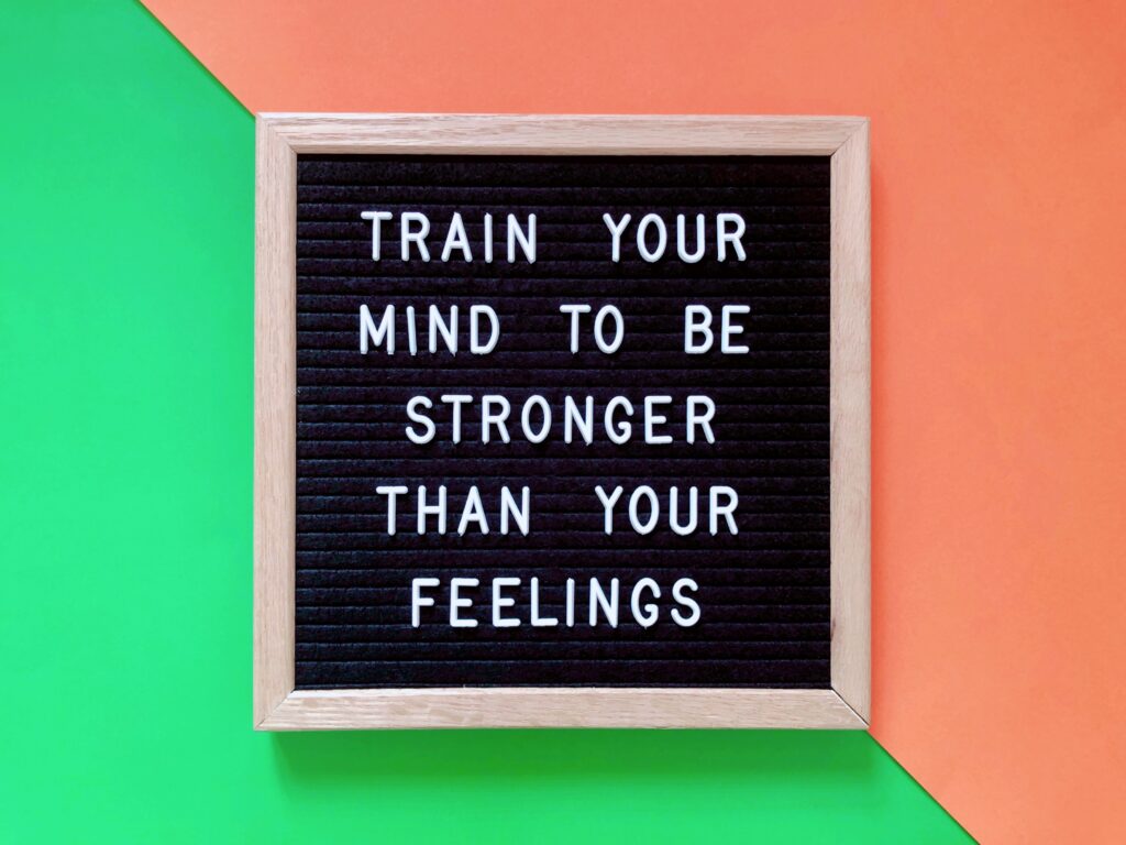 Schild auf orangem und grünem Hintergrund mit der Aufschrift: Train your mind to be stronger than your feelings