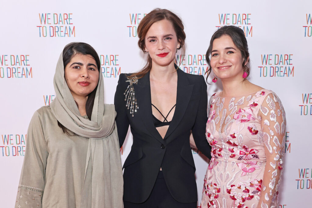 Emma Watson mit einem schwarzem Kleid steht mit zwei anderen Frauen zusammen