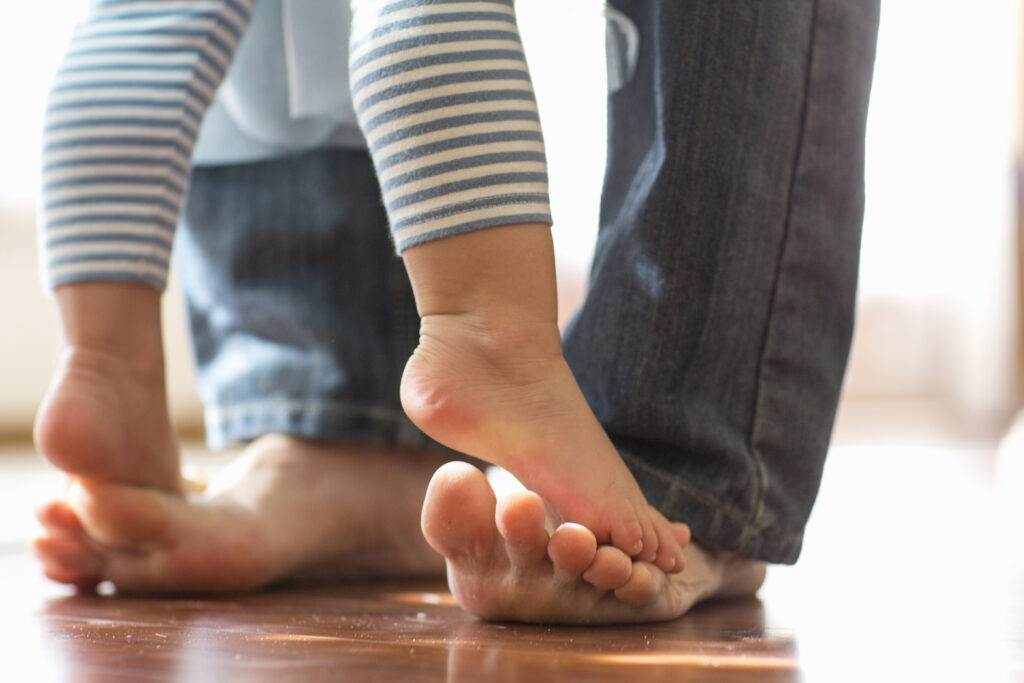 Babyfüsse tehen auf Erwachsenenfüssen