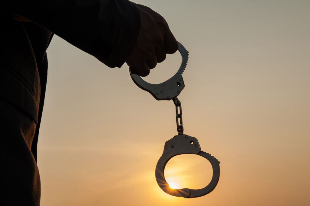 Mann hält Handschellen in der Hand bei Sonnenuntergang